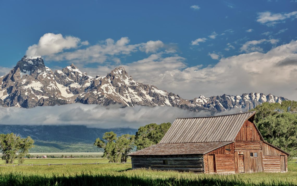 Old Mormon Barn In Grand Teton Mountains With Low Clouds. Grand