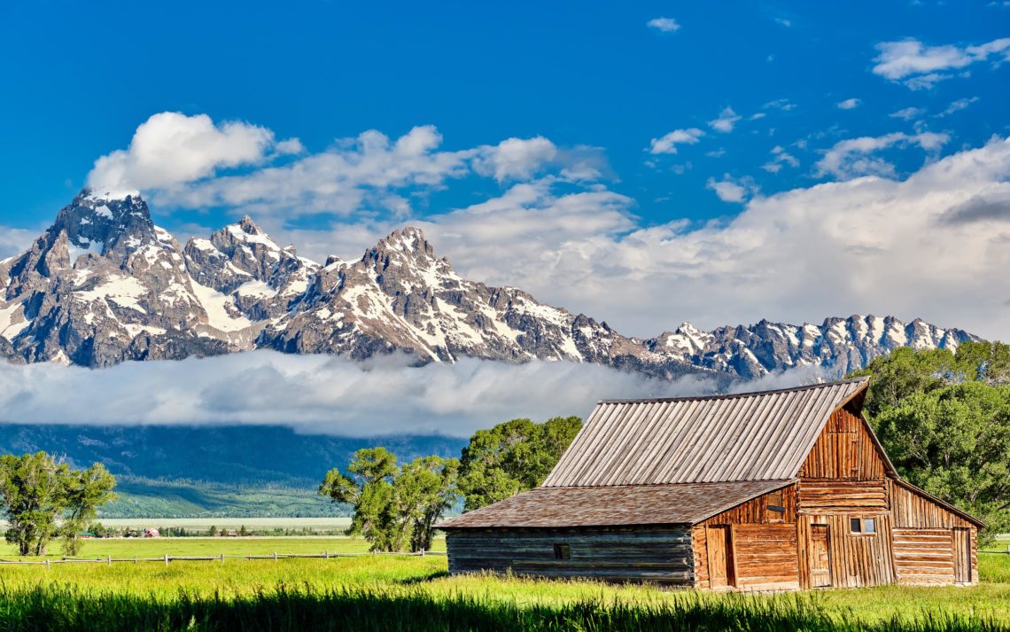 Old Mormon Barn In Grand Teton Mountains With Low Clouds. Grand