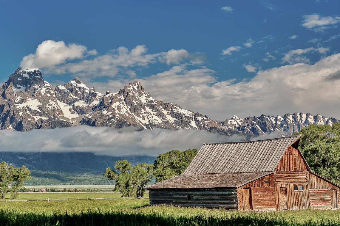 Old Mormon Barn In Grand Teton Mountains With Low Clouds. Grand